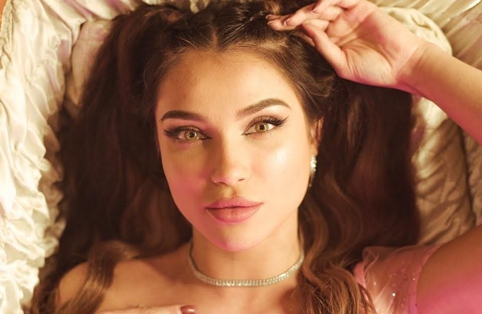 Natalia Karczmarczyk (Natsu) przeglądająca swój profil na Instagramie (@natalia.karczmarczyk) na telefonie, uśmiechnięta, w tle rozmyte nowoczesne wnętrze, symbolizujące jej aktywność w mediach społecznościowych.