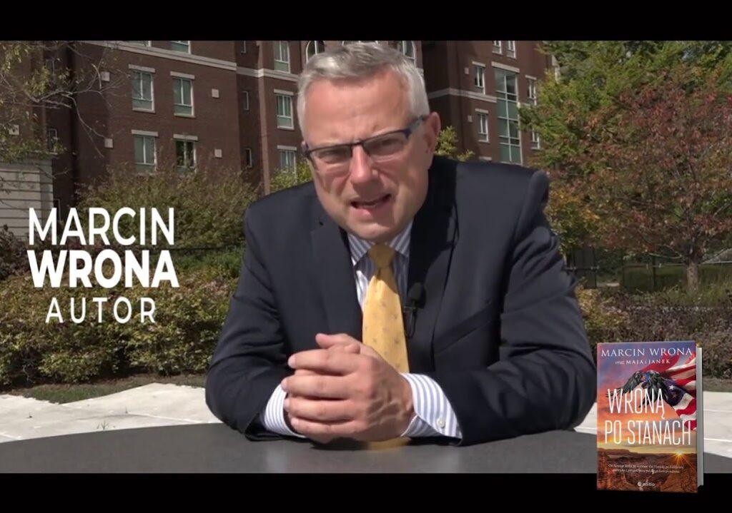 Marcin Wrona relacjonujący na żywo, trzymający mikrofon z logo TVN.
