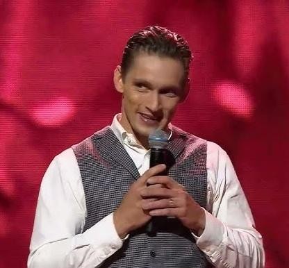 Filip Gurłacz na scenie, w trakcie występu, oświetlony reflektorami, oddający energię i talent aktora.