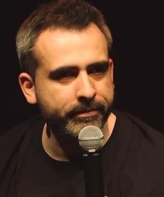 Abelard Giza na scenie podczas występu stand-upowego, dynamicznie angażujący publiczność.