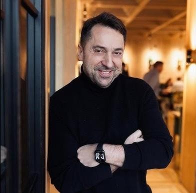 Marcin Miller w swobodnej chwili, uśmiechnięty, w otoczeniu luksusowego samochodu lub w domowym zaciszu w Ełku, symbolizujący jego optymizm i zamiłowanie do motoryzacji.