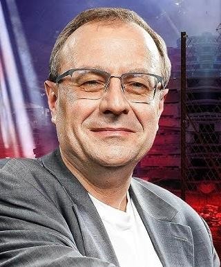 Antoni Dudek podczas wykładu, gestykulujący, w tle sala wykładowa z publicznością.