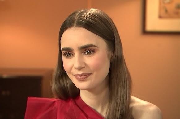 Lily Collins z książką lub notatnikiem, w zamyślonej pozie, symbolizująca jej zainteresowania literackie.