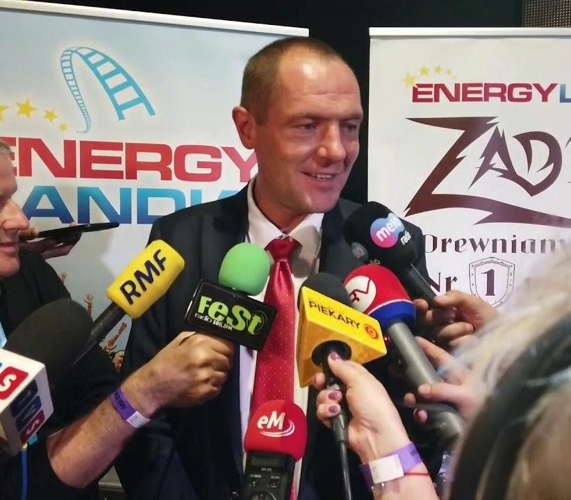Dynamiczne ujęcie Energylandii, największego parku rozrywki w Polsce, z widokiem na kolejkę górską i inne atrakcje, oddające wibrację i skalę miejsca.